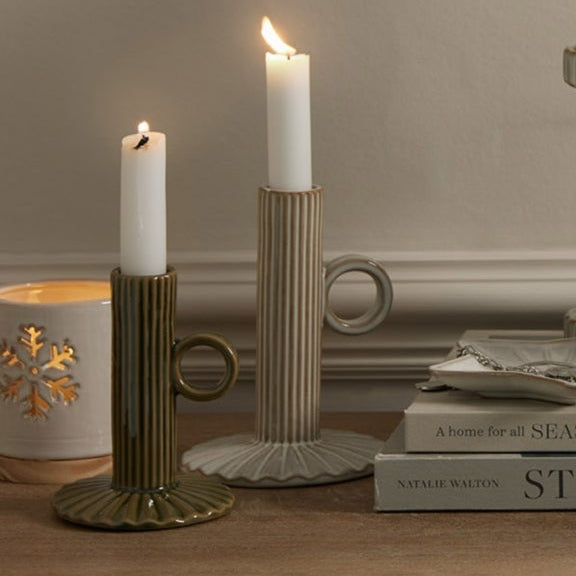 Candles in various holders on a wooden surface with a neutral background